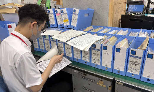 写真：職員が紙の報告書を確認する様子