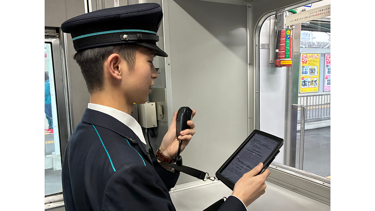 写真：Handbook X に登録した業務資料をもとに車内放送をする様子